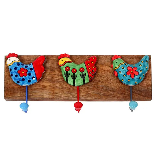 A rustic wooden wall hook rack featuring three hand-painted decorative chickens in blue, green, and turquoise with red accents and hanging hooks.