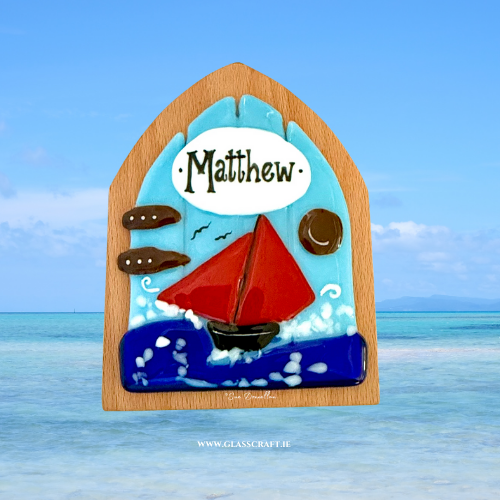 Decorative door with a sailboat design and the name 'Matthew' against a blue ocean background.
