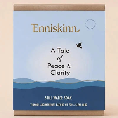 Enniskinn 'A Tale of Peace & Clarity' Still Water Soak packaging box, featuring a light blue and navy blue design with a brown kraft paper top and bottom, set against a solid beige background.